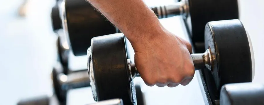 A hand lifting a dumbbell from a rack