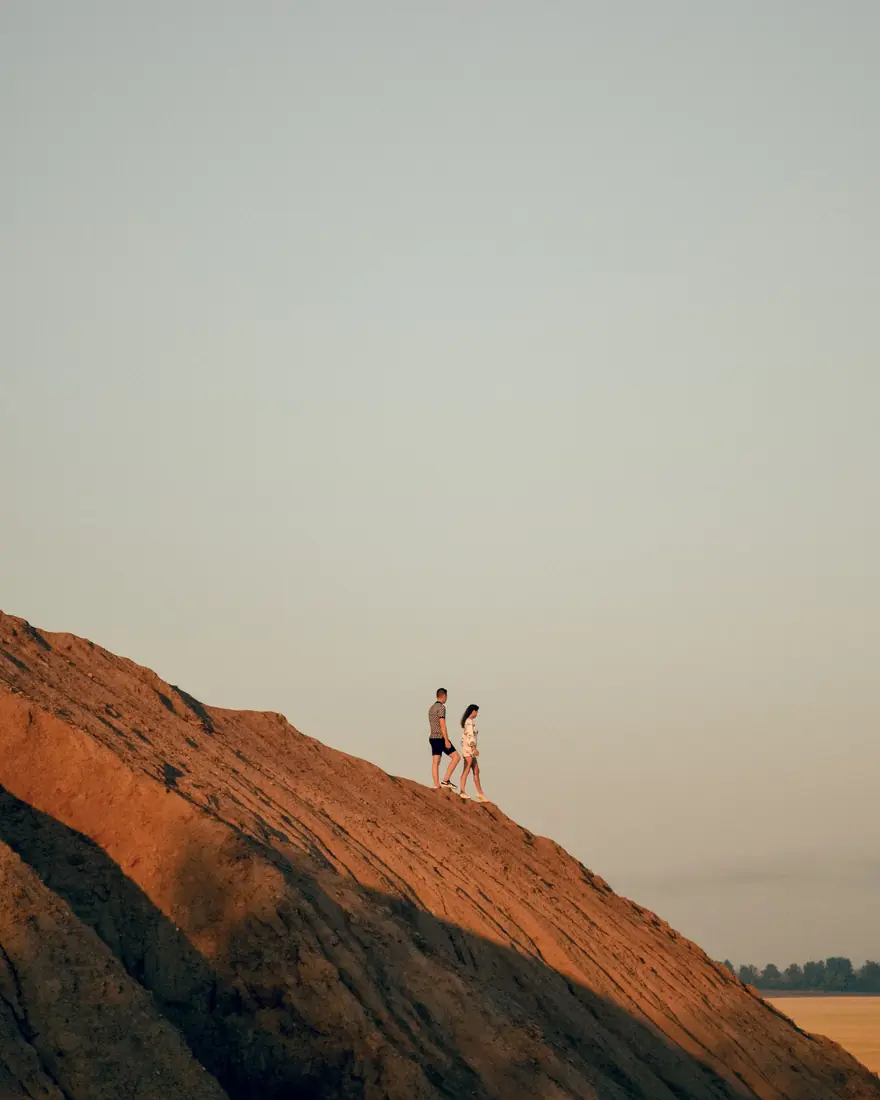 A man and a woman walking together along a ridge at sunset